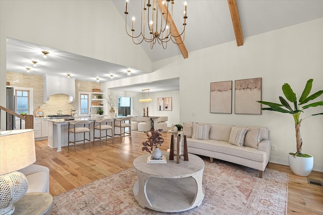 living room featuring beam ceiling, high vaulted ceiling, and light wood-type flooring