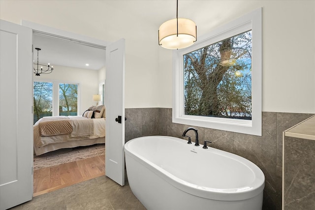 bathroom with a bathing tub, hardwood / wood-style floors, and tile walls