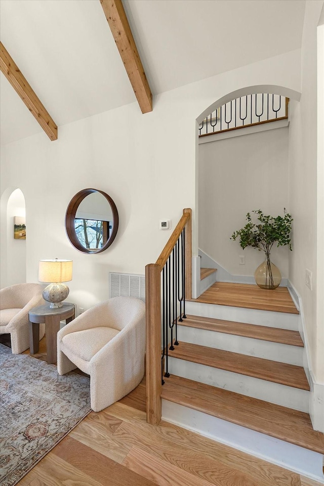 stairs with beamed ceiling and hardwood / wood-style flooring