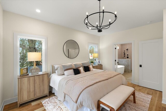 bedroom featuring ensuite bathroom, a chandelier, and light hardwood / wood-style flooring