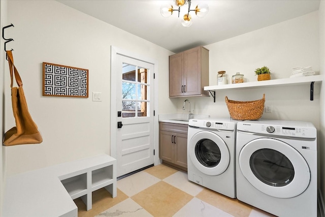 laundry room with an inviting chandelier, cabinets, sink, and washing machine and dryer