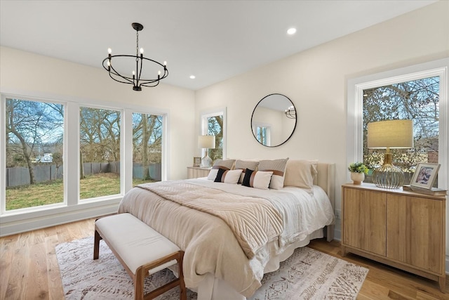 bedroom featuring multiple windows, a chandelier, and light hardwood / wood-style floors