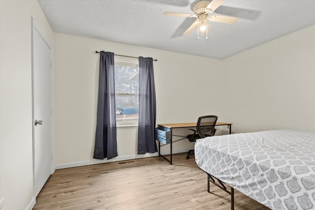 bedroom featuring ceiling fan, a textured ceiling, and light wood-type flooring