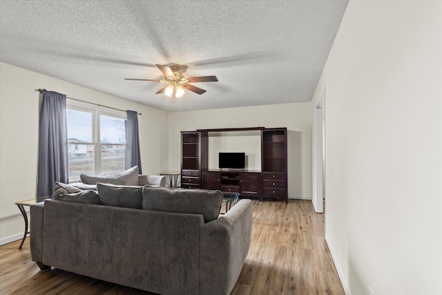 living room with ceiling fan, a textured ceiling, and light hardwood / wood-style floors