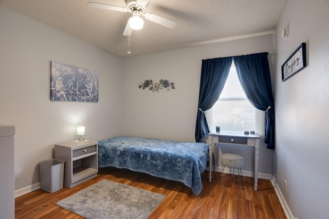 bedroom with a textured ceiling, wood-type flooring, and ceiling fan