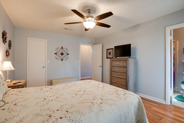 bedroom with ceiling fan, light hardwood / wood-style floors, and a textured ceiling