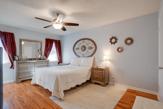 bedroom with ceiling fan, a textured ceiling, and light wood-type flooring