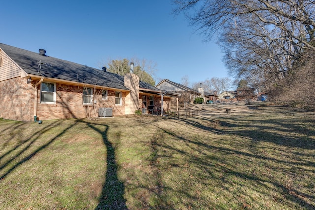 rear view of property with a yard and central air condition unit