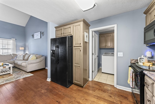 kitchen featuring dark wood-type flooring, black appliances, a textured ceiling, washer / dryer, and cream cabinetry