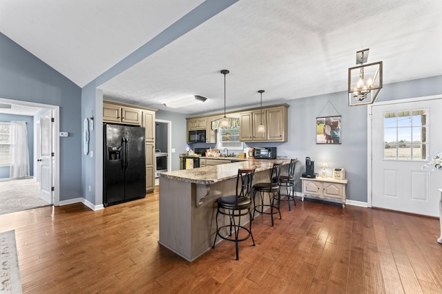 kitchen featuring pendant lighting, black appliances, a kitchen breakfast bar, kitchen peninsula, and dark wood-type flooring