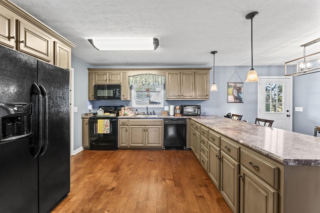 kitchen with sink, dark hardwood / wood-style flooring, kitchen peninsula, pendant lighting, and black appliances