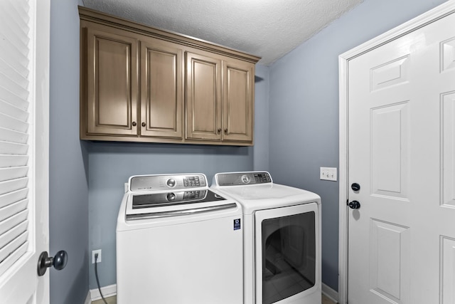 washroom with cabinets, washer and dryer, and a textured ceiling