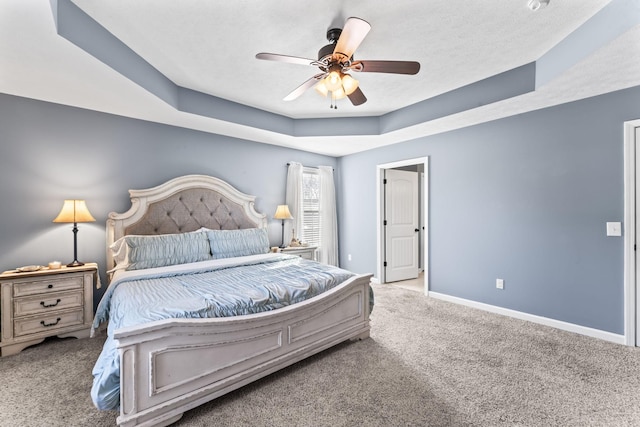 carpeted bedroom featuring a raised ceiling, a textured ceiling, and ceiling fan