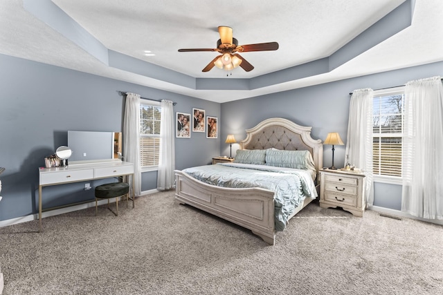 bedroom with a tray ceiling, ceiling fan, and carpet