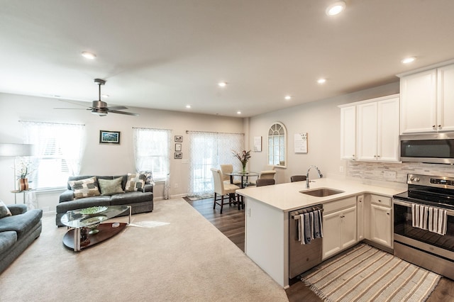 kitchen featuring appliances with stainless steel finishes, sink, white cabinets, and kitchen peninsula