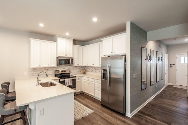 kitchen featuring a kitchen bar, sink, kitchen peninsula, stainless steel appliances, and white cabinets