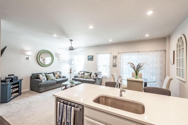 kitchen featuring ceiling fan, light colored carpet, dishwasher, and sink