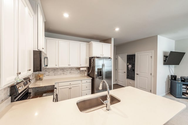 kitchen featuring appliances with stainless steel finishes, white cabinetry, sink, decorative backsplash, and kitchen peninsula