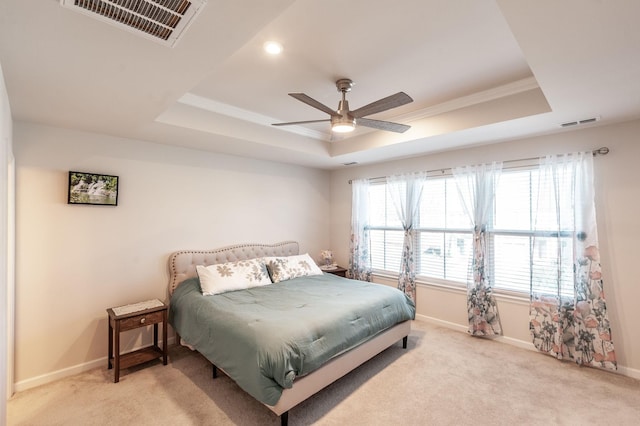 bedroom featuring light colored carpet, a raised ceiling, and ceiling fan