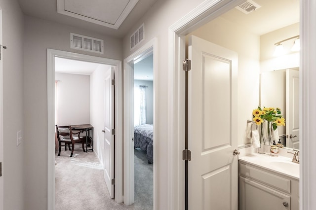 corridor featuring light colored carpet and sink