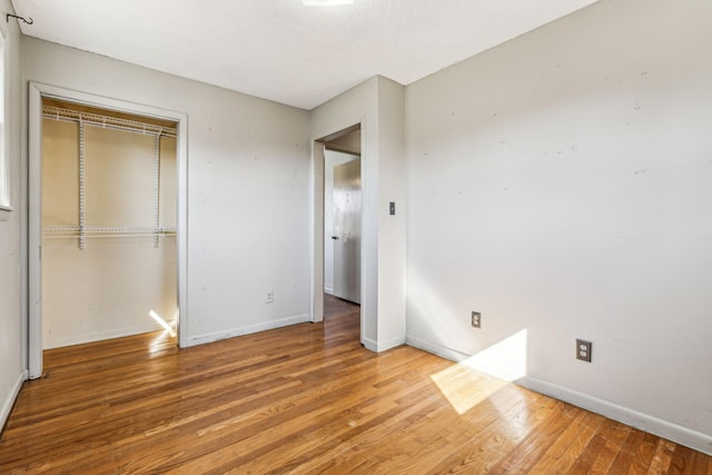 unfurnished bedroom featuring hardwood / wood-style floors, a closet, and baseboards