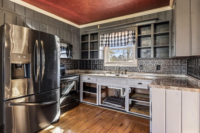 kitchen with stainless steel appliances, ornamental molding, a sink, and dark wood-style floors