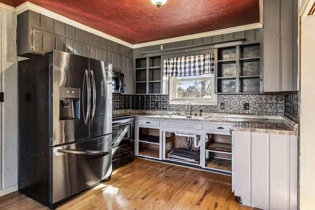 kitchen with ornamental molding, wood finished floors, stainless steel appliances, a textured ceiling, and a sink