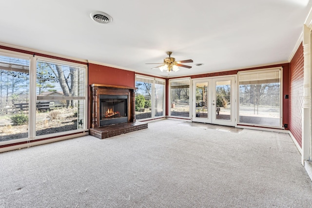 unfurnished living room with carpet, visible vents, ornamental molding, a brick fireplace, and ceiling fan