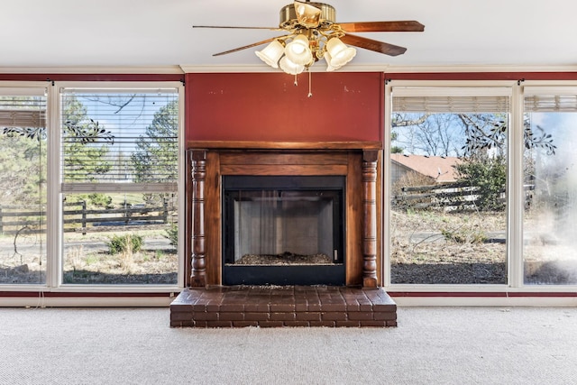 details with a brick fireplace, crown molding, ceiling fan, and carpet flooring