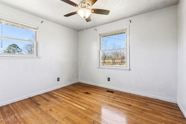 spare room with light wood-type flooring, baseboards, visible vents, and a ceiling fan