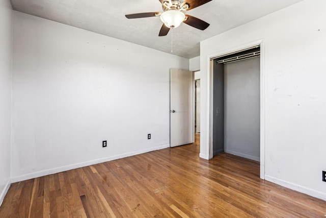 unfurnished bedroom featuring ceiling fan, a closet, wood finished floors, and baseboards