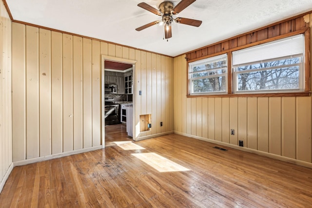 spare room featuring a ceiling fan, visible vents, baseboards, and hardwood / wood-style flooring