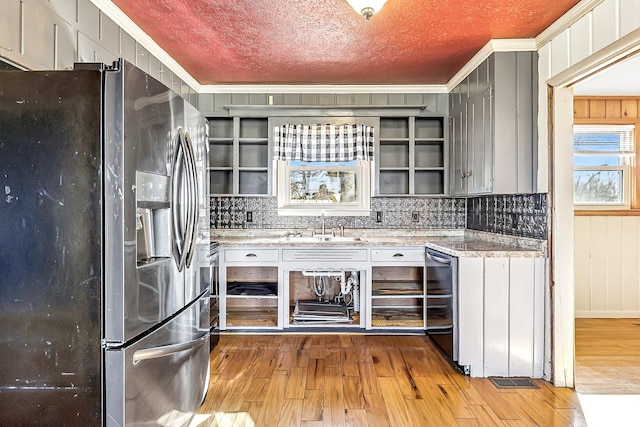 kitchen featuring crown molding, a sink, light wood finished floors, and stainless steel fridge with ice dispenser