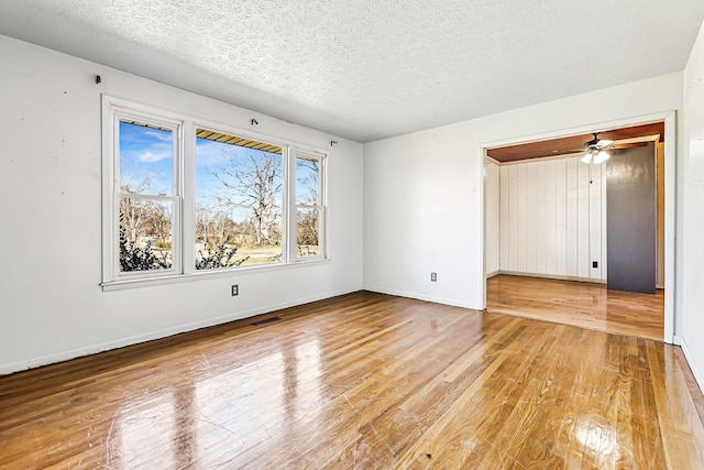 unfurnished room featuring hardwood / wood-style flooring, baseboards, visible vents, and a textured ceiling