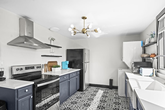 kitchen with appliances with stainless steel finishes, a chandelier, hanging light fixtures, and wall chimney range hood