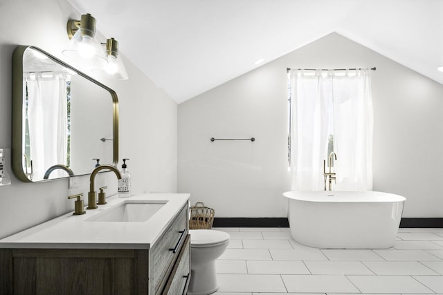 bathroom featuring vaulted ceiling, a bathtub, vanity, toilet, and tile patterned floors