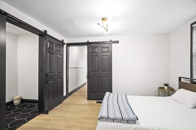 bedroom featuring a barn door and hardwood / wood-style floors