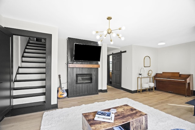 living room featuring light hardwood / wood-style flooring, a barn door, and a chandelier