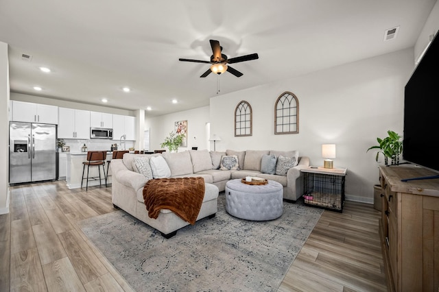 living room with ceiling fan, sink, and light hardwood / wood-style flooring