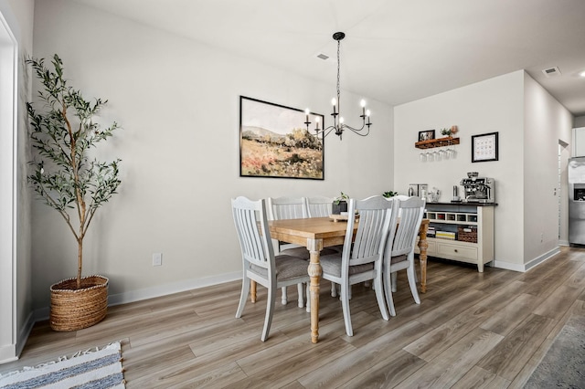 dining space featuring wood-type flooring and an inviting chandelier