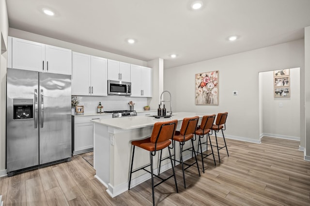 kitchen featuring appliances with stainless steel finishes, a breakfast bar, sink, white cabinets, and a center island with sink