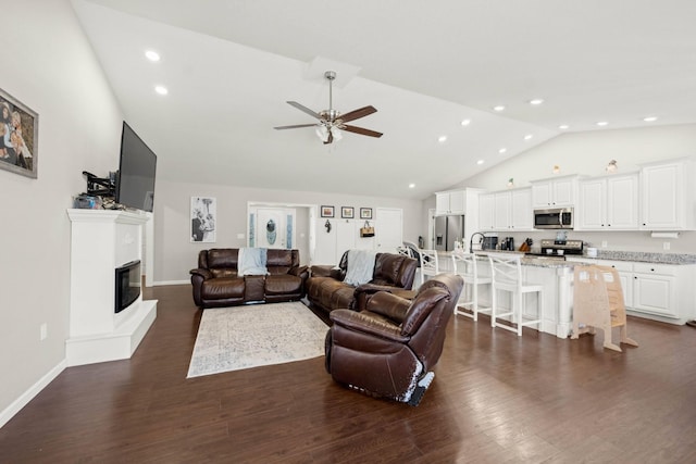 living room with ceiling fan, dark hardwood / wood-style flooring, and high vaulted ceiling