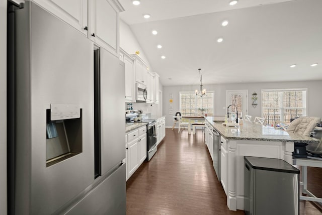 kitchen featuring white cabinets, stainless steel appliances, a kitchen bar, and a large island with sink