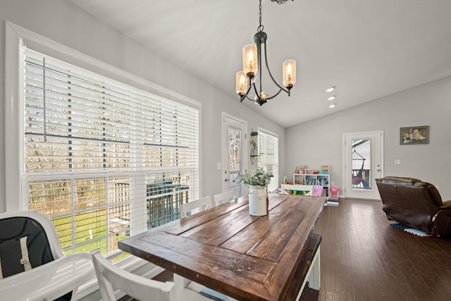 dining space featuring vaulted ceiling, dark hardwood / wood-style flooring, and an inviting chandelier