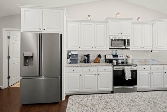 kitchen featuring lofted ceiling, dark wood-type flooring, appliances with stainless steel finishes, white cabinetry, and light stone counters