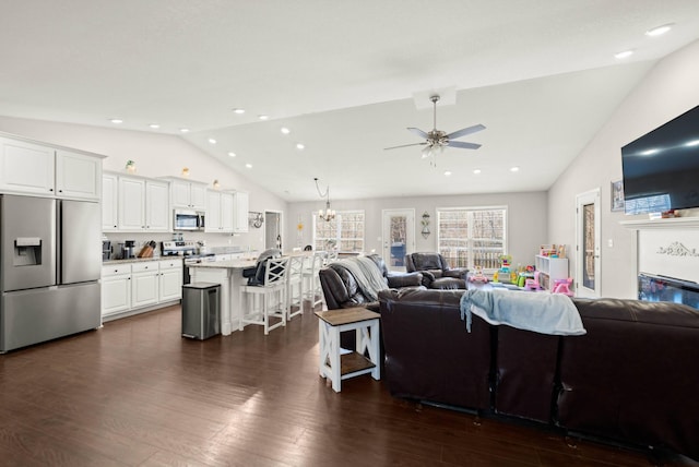 living room with lofted ceiling, ceiling fan with notable chandelier, and dark wood-type flooring