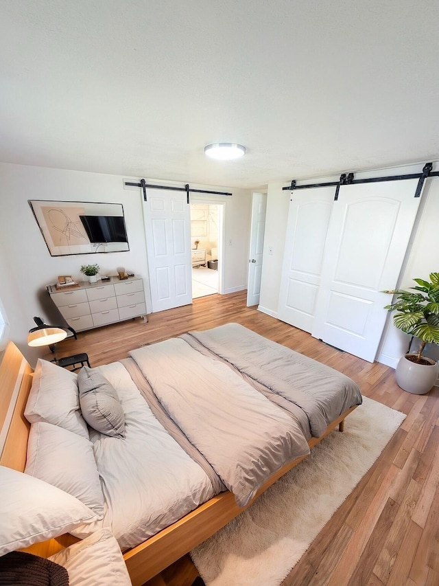 bedroom featuring a barn door and light wood-type flooring