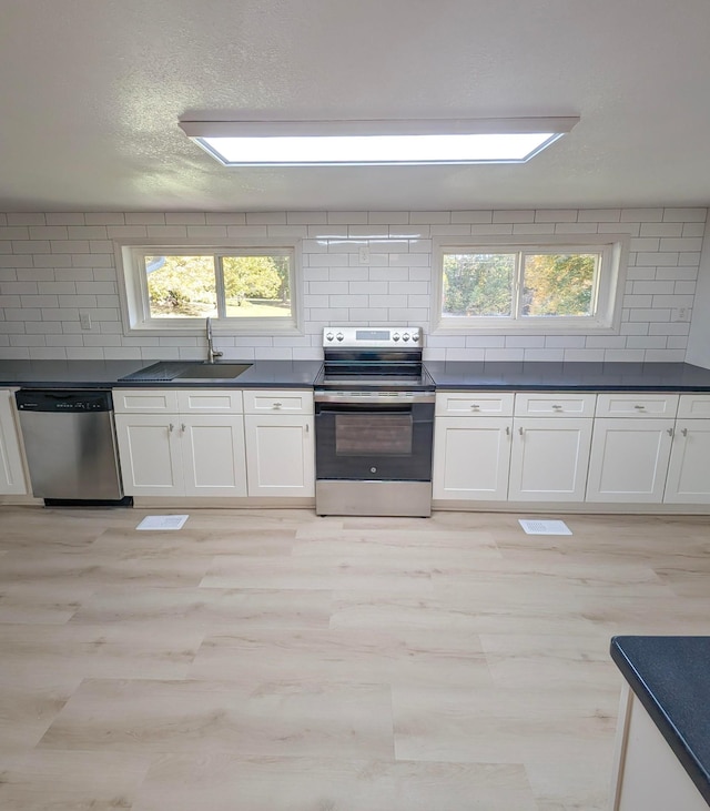 kitchen with tasteful backsplash, white cabinetry, appliances with stainless steel finishes, and sink