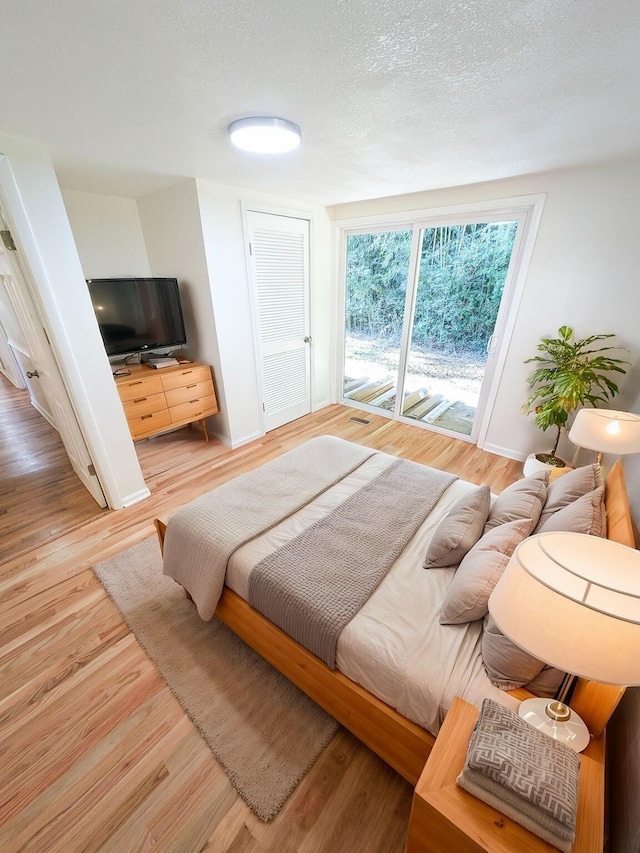 bedroom with hardwood / wood-style flooring, access to exterior, and a textured ceiling