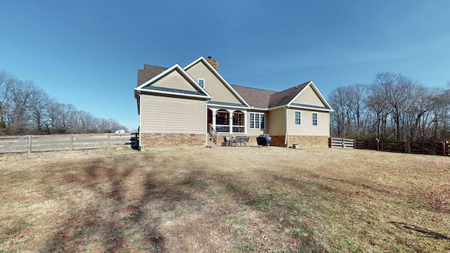 back of property with crawl space, a chimney, fence, and a lawn